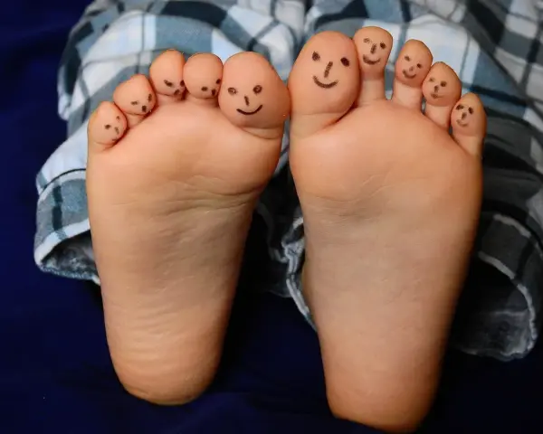 Caritas sonrientes en los dedos de bebés descalzos en invierno, jugando con sus pies.