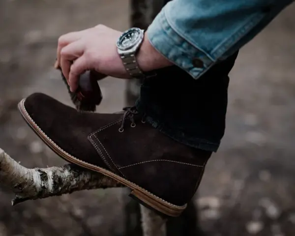 Hombre cepillando bota de cuero marrón, un paso esencial para saber como limpiar botas de cuero y mantenerlas impecables.