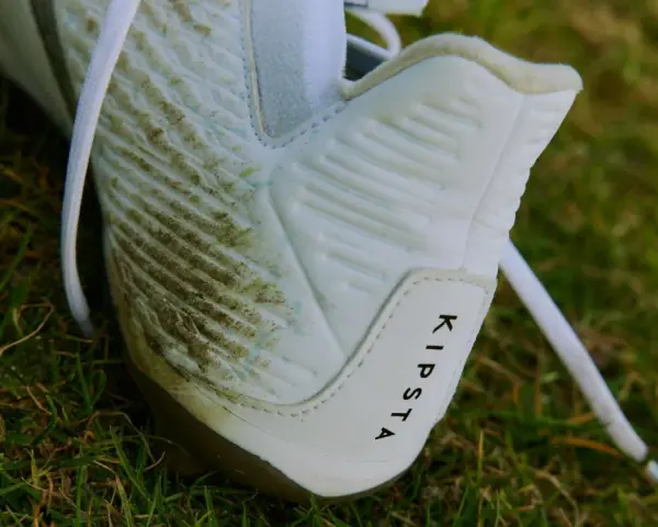 Botines blancos Kipsta con manchas de césped, listos para limpiar.