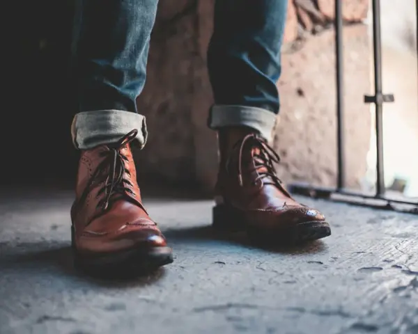 Un outfit con botines hombre: jeans doblados y botines de cuero marrón con cordones, listos para la aventura urbana.