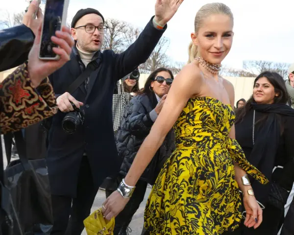 Mujer con un llamativo vestido globo amarillo y negro, rodeada de gente y fotógrafos.