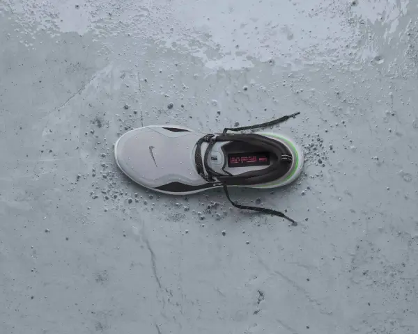 Zapatilla Nike gris con detalles verdes y negros, mojada y con gotas de agua. ¡Perfecta para que se puedan meter las zapatillas en la secadora sin problema!