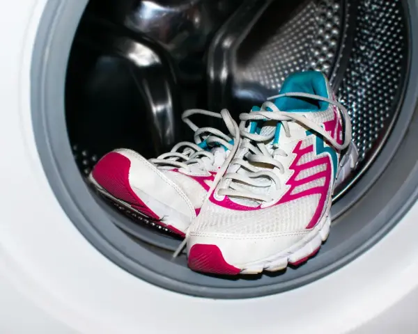 Zapatillas deportivas blancas con detalles fucsia y turquesa listas para aprender como lavar zapatillas en la lavadora.