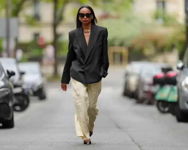 Mujer con blazer negro y pantalones de lino a rayas. Aprende como lavar pantalones de lino para mantenerlos impecables.
