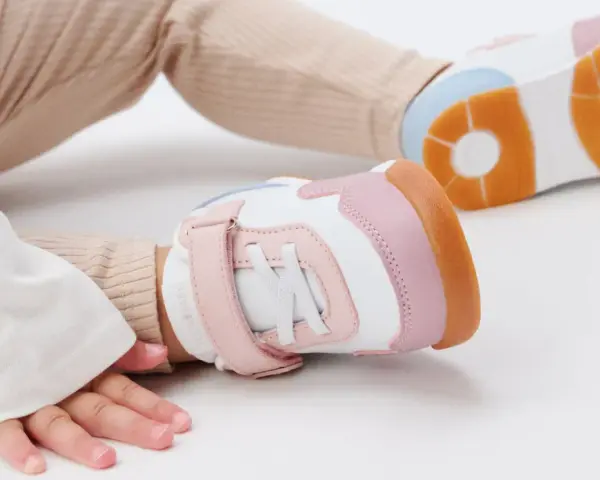 Unas zapatillas de calzado de bebé en tonos blanco, rosa y naranja, listas para los primeros pasos.