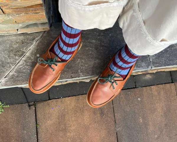 Mocasines de cuero marrón con cordones verdes y calcetines a rayas. Una idea de cómo combinar mocasines mujer para un look casual y chic.