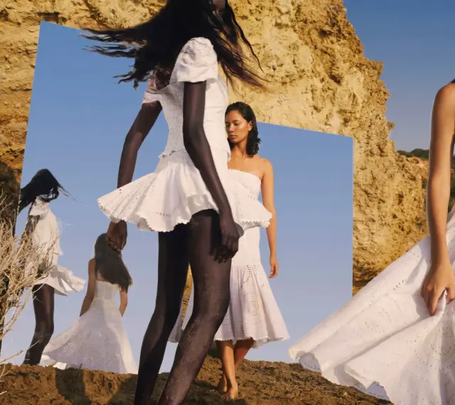 Modelos con vestidos blancos de **Charo Ruiz Ibiza** en un paisaje rocoso, reflejadas en un espejo.