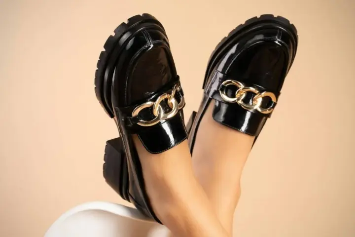 Zapatos negros de charol con cadena dorada, perfectos para aprender como limpiar zapatos de charol y mantener su brillo.
