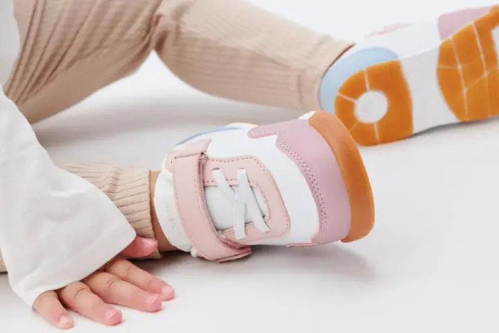 Unas zapatillas de calzado de bebé en tonos blanco, rosa y naranja, listas para los primeros pasos.