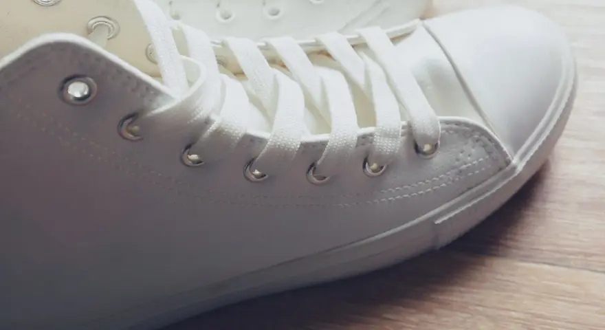 Primer plano de unas zapatillas blancas de tela, listas para limpiar y lucir impecables.