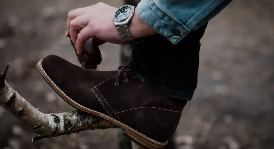 Hombre cepillando bota de cuero marrón, un paso esencial para saber como limpiar botas de cuero y mantenerlas impecables.