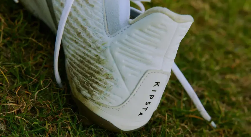 Botines blancos Kipsta con manchas de césped, listos para limpiar.