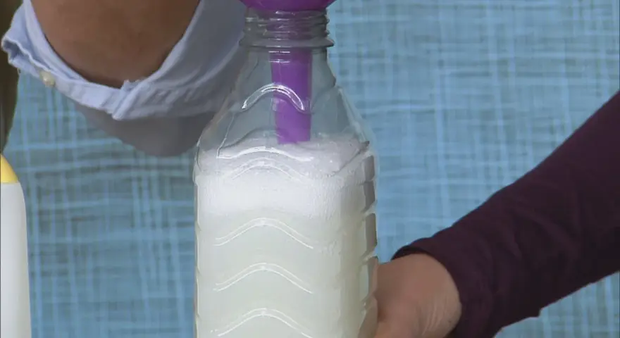 Vertiendo líquido en una botella para crear alternativas al suavizante.