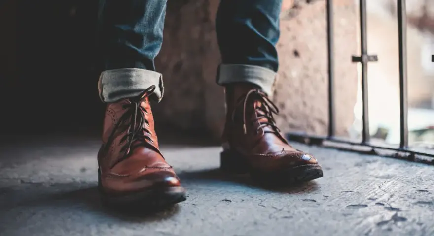 Un outfit con botines hombre: jeans doblados y botines de cuero marrón con cordones, listos para la aventura urbana.