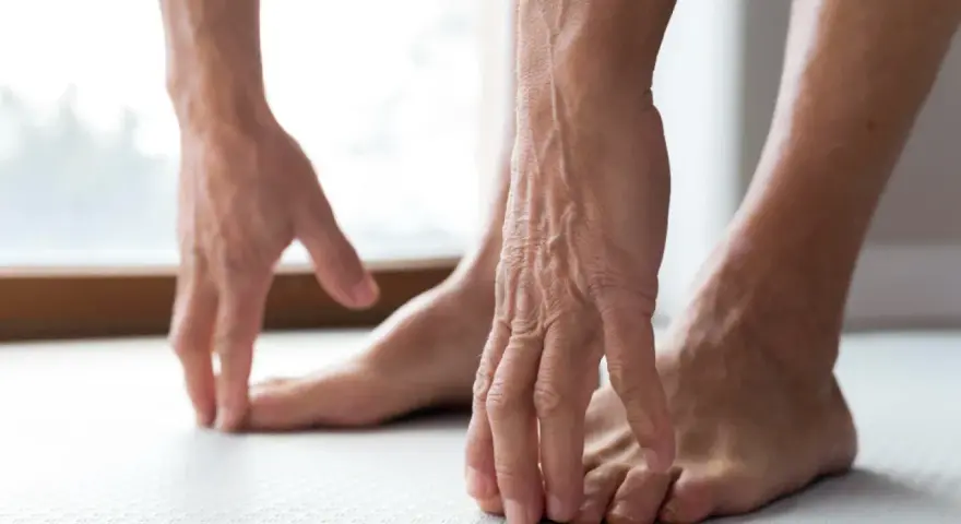 Manos tocando los dedos de los pies, como si sintiera las rampas en los pies.