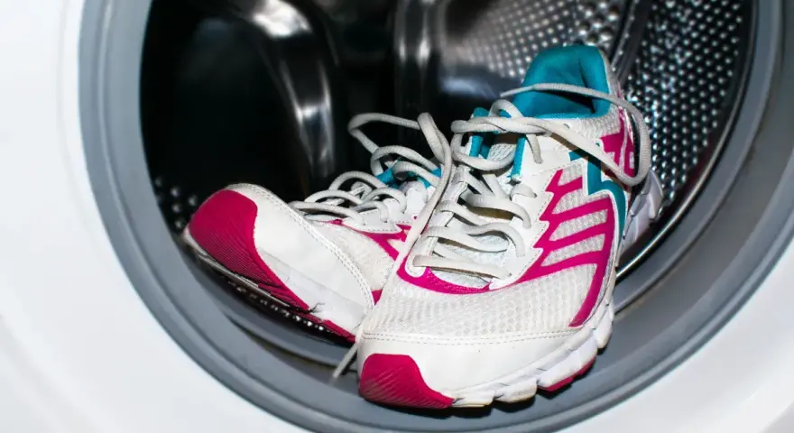 Zapatillas deportivas blancas con detalles fucsia y turquesa listas para aprender como lavar zapatillas en la lavadora.