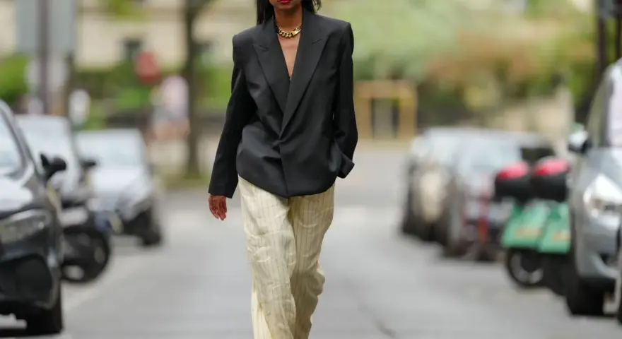 Mujer con blazer negro y pantalones de lino a rayas. Aprende como lavar pantalones de lino para mantenerlos impecables.