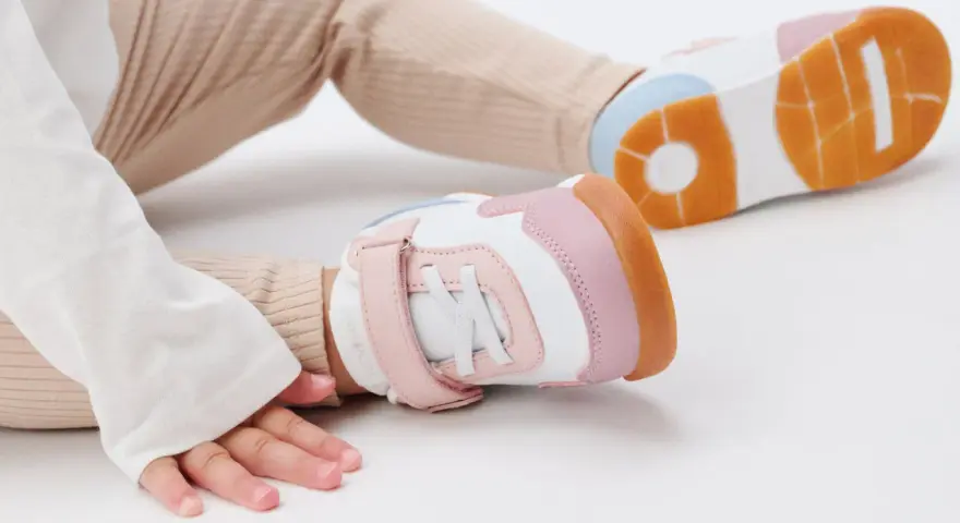 Unas zapatillas de calzado de bebé en tonos blanco, rosa y naranja, listas para los primeros pasos.