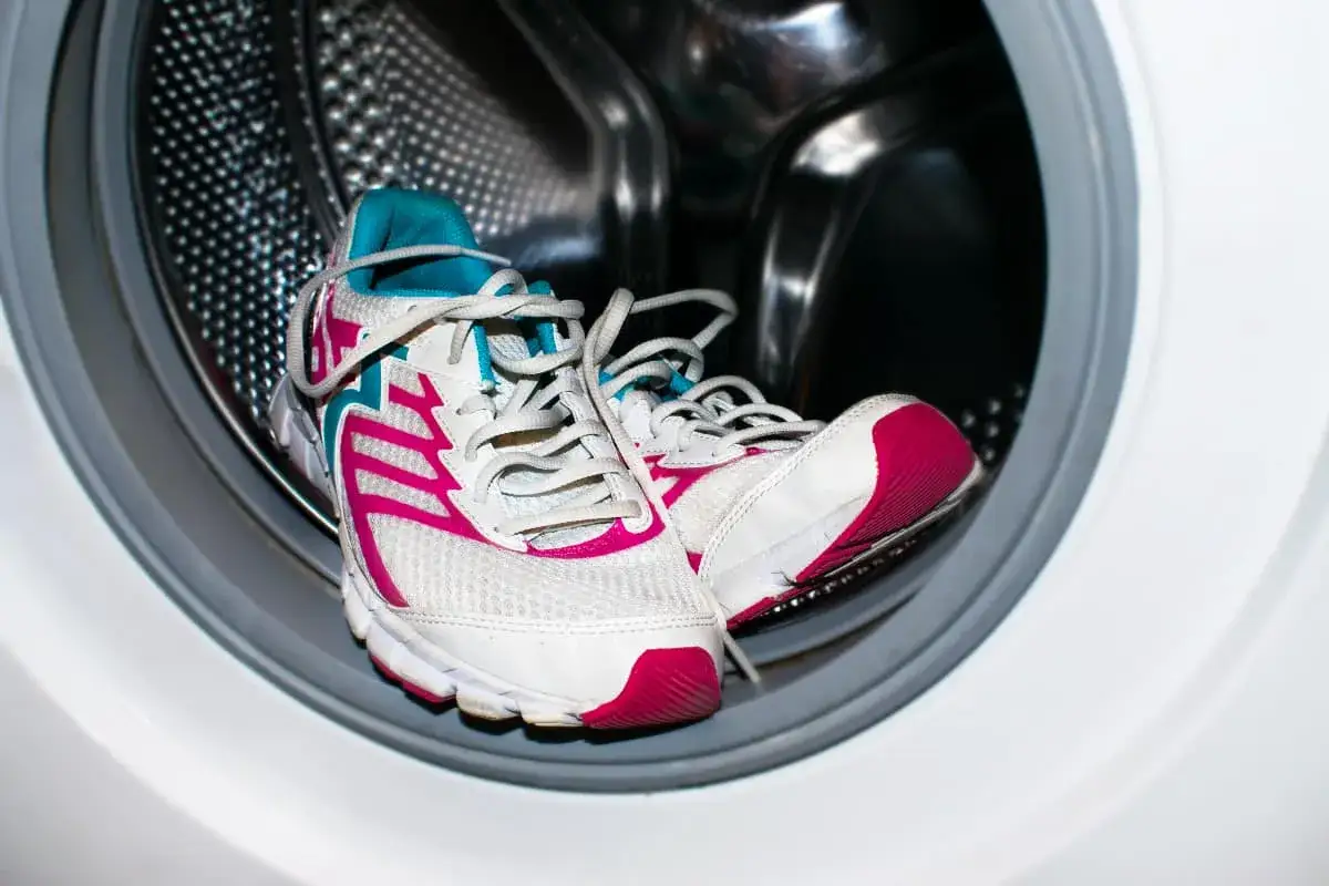 Zapatillas deportivas blancas con detalles fucsia y turquesa listas para lavar. &iquest;A qu&eacute; temperatura lavar zapatillas? Fr&iacute;o o 30&deg;C es ideal.