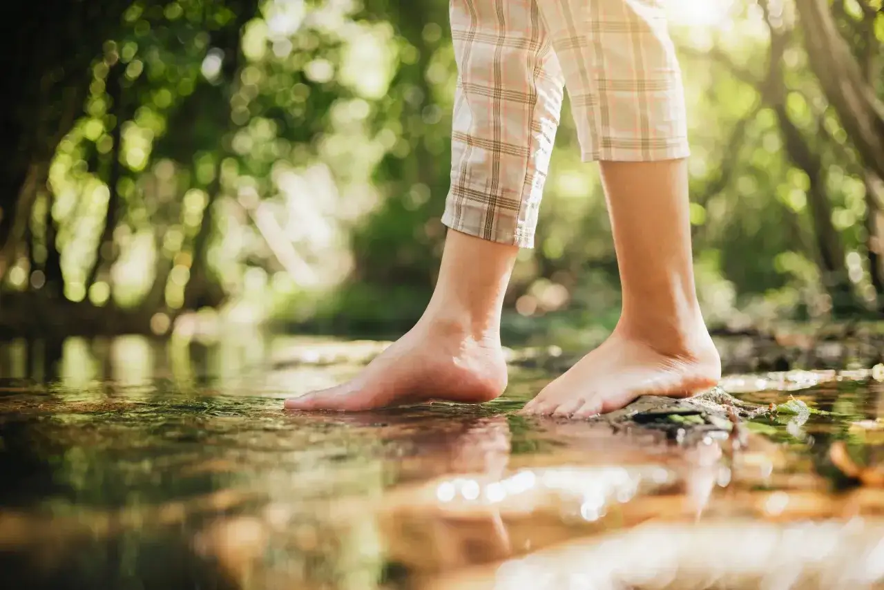 Pies descalzos sobre el agua de un arroyo, sintiendo la frescura. Es bueno andar descalzo en la naturaleza.
