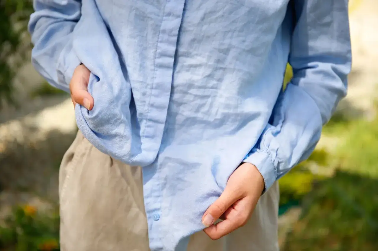 Persona alisando su camisa azul arrugada, mostrando cómo planchar ropa sin plancha.
