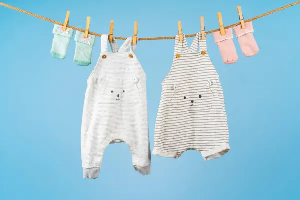 Ropa de bebé colgada para secar: dos peleles con caritas de oso y calcetines a juego. ¡El momento perfecto para saber cuando lavar la ropa del bebé!