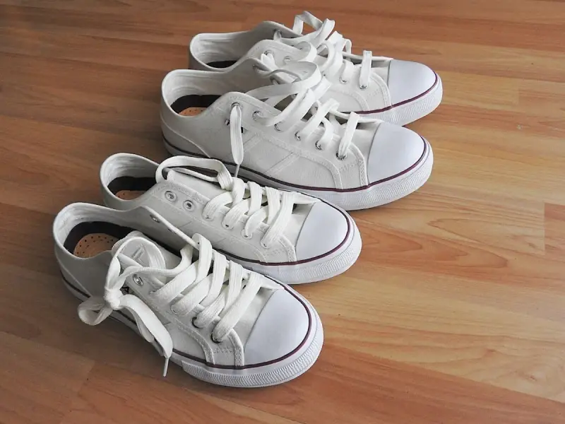 Cuatro zapatillas blancas de lona, listas para limpiar y lucir impecables.